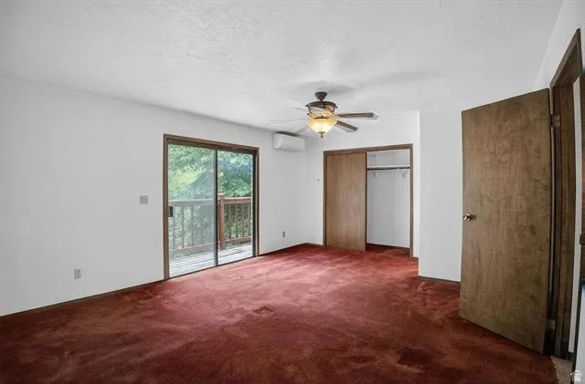 Spacious interior featuring a sliding glass door to an exterior deck, soft red carpeting, a ceiling fan with integrated lighting, and a built-in closet with bi-fold doors