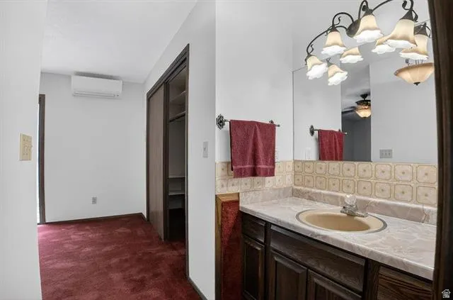 Vanity with an integrated sink, patterned tile backsplash, and an ornate, multi-bulb light fixture