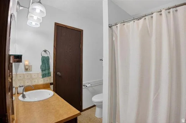 Bathroom featuring a vanity with an integrated sink, a dark wood-finish door, and a shower area with a curtain rod