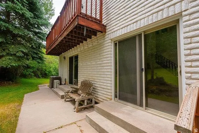 Exterior featuring a white brick facade, two sets of sliding glass doors, and a concrete patio
