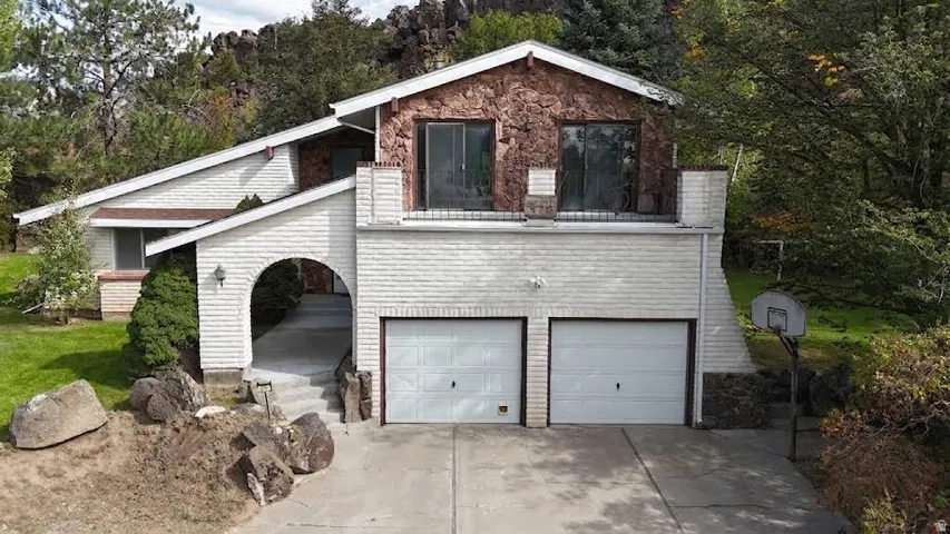 Multi-level residence featuring a two-car garage, stone and white brick exterior accents, and an upper-level balcony
