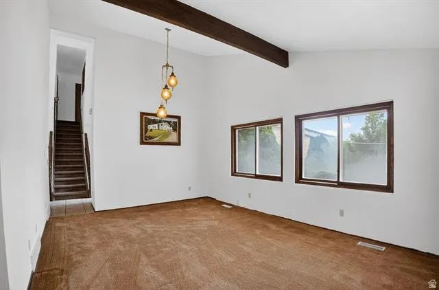 Room with vaulted ceiling, exposed wood beam, and brown carpeting