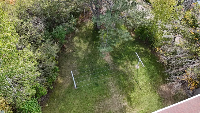 Expansive backyard featuring a manicured lawn, established trees, and a clothesline