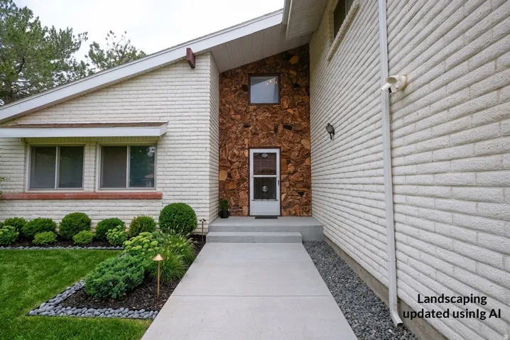 White brick exterior with a stone accent entry, concrete walkway, and manicured landscaping featuring varied plantings