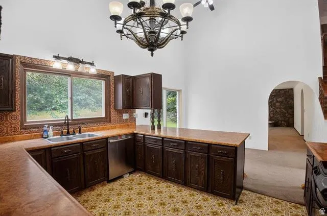 Kitchen featuring dark wood cabinetry, a double basin stainless steel sink with a matte black faucet, and a stainless steel dishwasher