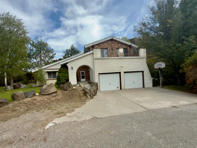 Two-car attached garage, stone veneer siding, brick exterior, arched entry, mature trees