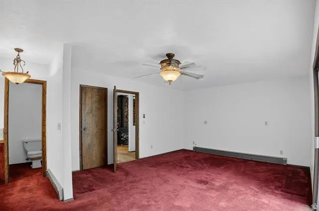 Spacious room featuring red carpeting, a ceiling fan with integrated lighting, and multiple wood-finish doorways