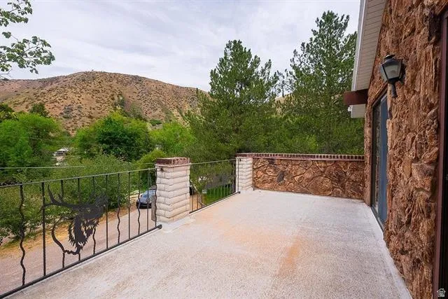 Outdoor balcony featuring a textured concrete surface, decorative wrought iron railing with elk motif, and stone-clad exterior wall