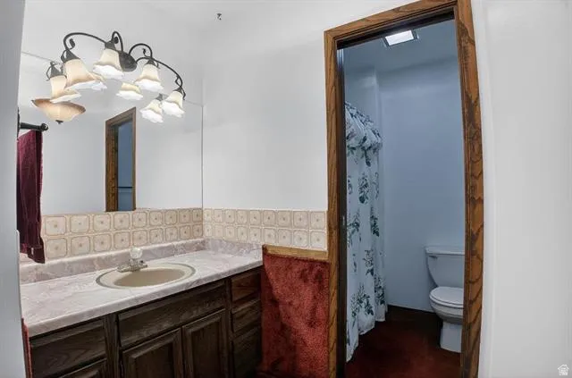 Bathroom featuring a dark wood vanity with a light-toned countertop, an oval sink, and a large wall mirror