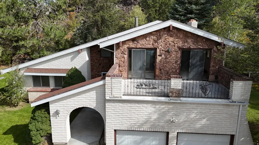 Two-story residence featuring a stone and brick exterior, two garage doors, and a second-level balcony with wrought iron railing