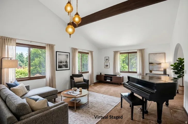 Vaulted ceiling with exposed beam, multiple windows providing natural light, archway leading to another space, and chandelier lighting fixtures