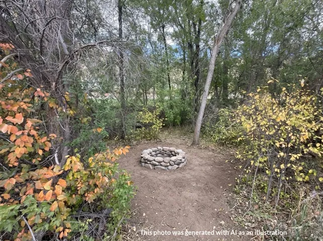 Stone-clad fire pit surrounded by natural landscaping and mature trees