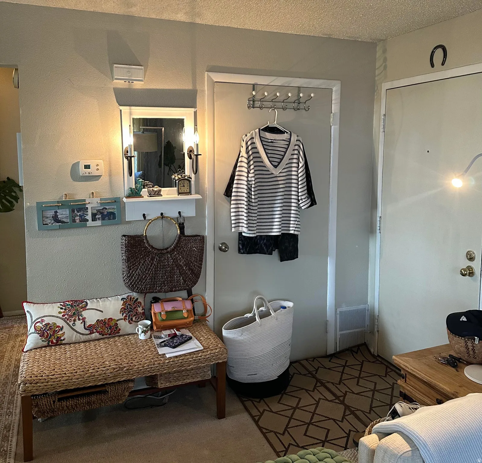 Entryway featuring a woven bench, a wall-mounted mirror with sconce lighting, and an overhead lighting fixture