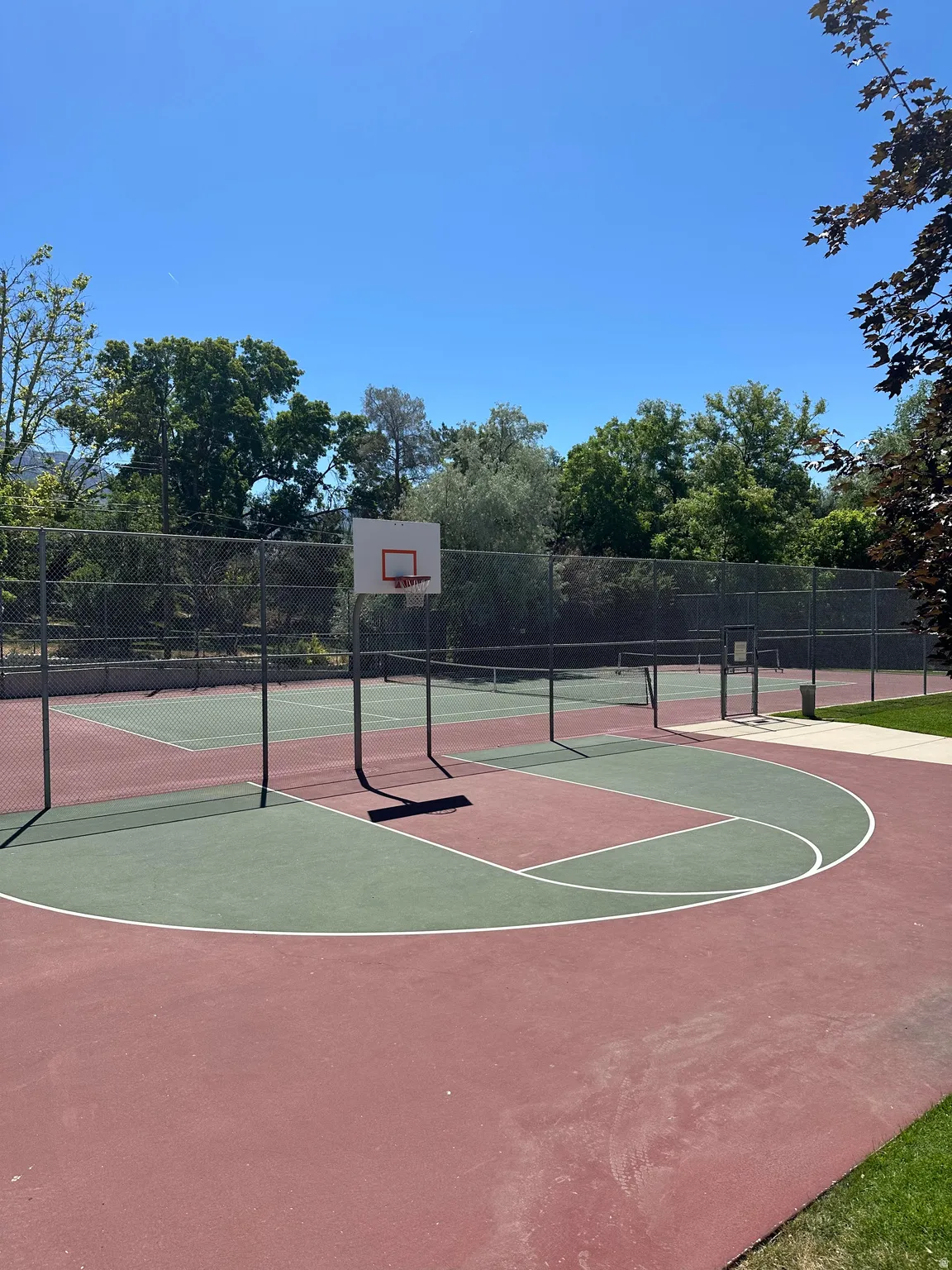 Multi-sport court featuring a basketball hoop and vibrant red and green surfacing