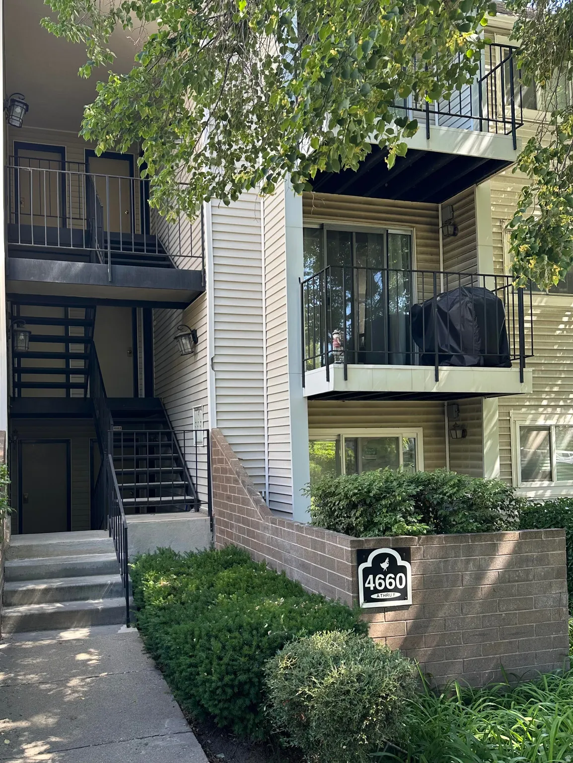 Multi-level residential building featuring tan siding and black exterior staircases