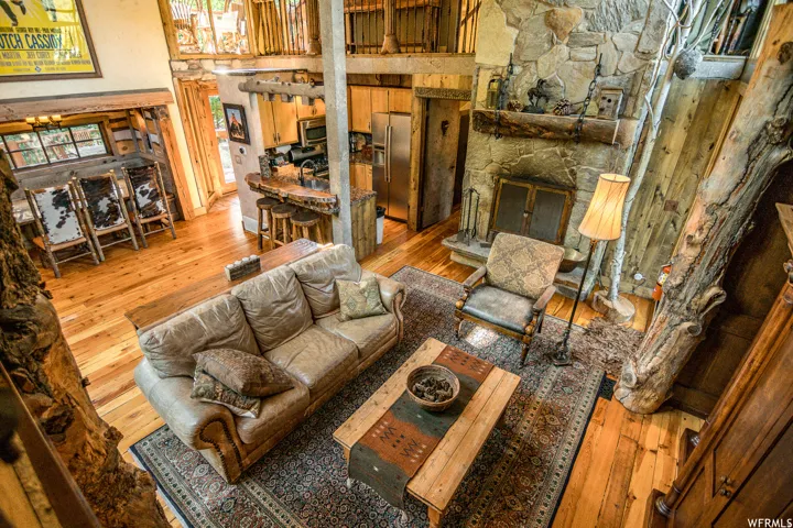 Spacious living area featuring high ceilings, natural wood-finish flooring, and a stone fireplace