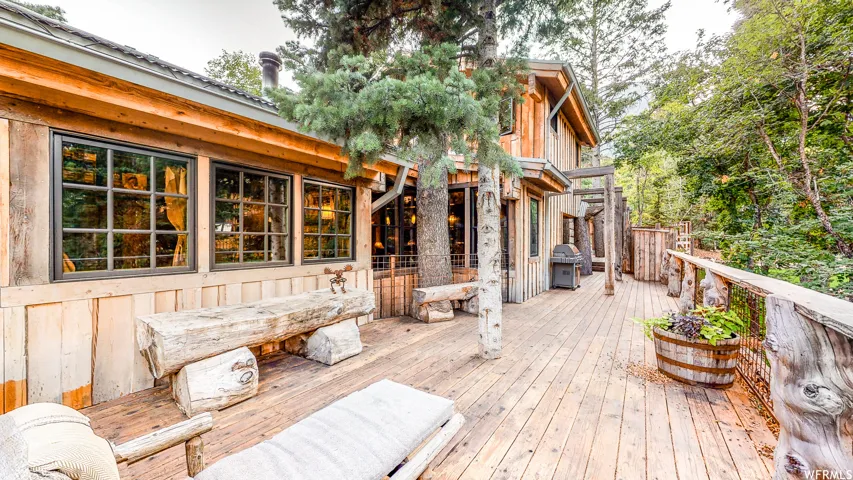 Expansive wood deck with a natural wood railing, featuring a log bench and a built-in barrel planter