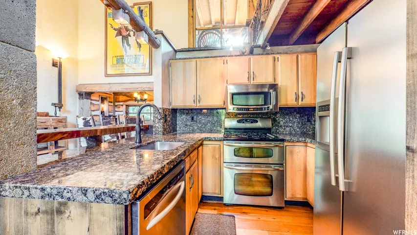 Kitchen featuring stone-finish countertops, stainless steel appliances, light wood cabinetry, a built-in microwave, and a double oven