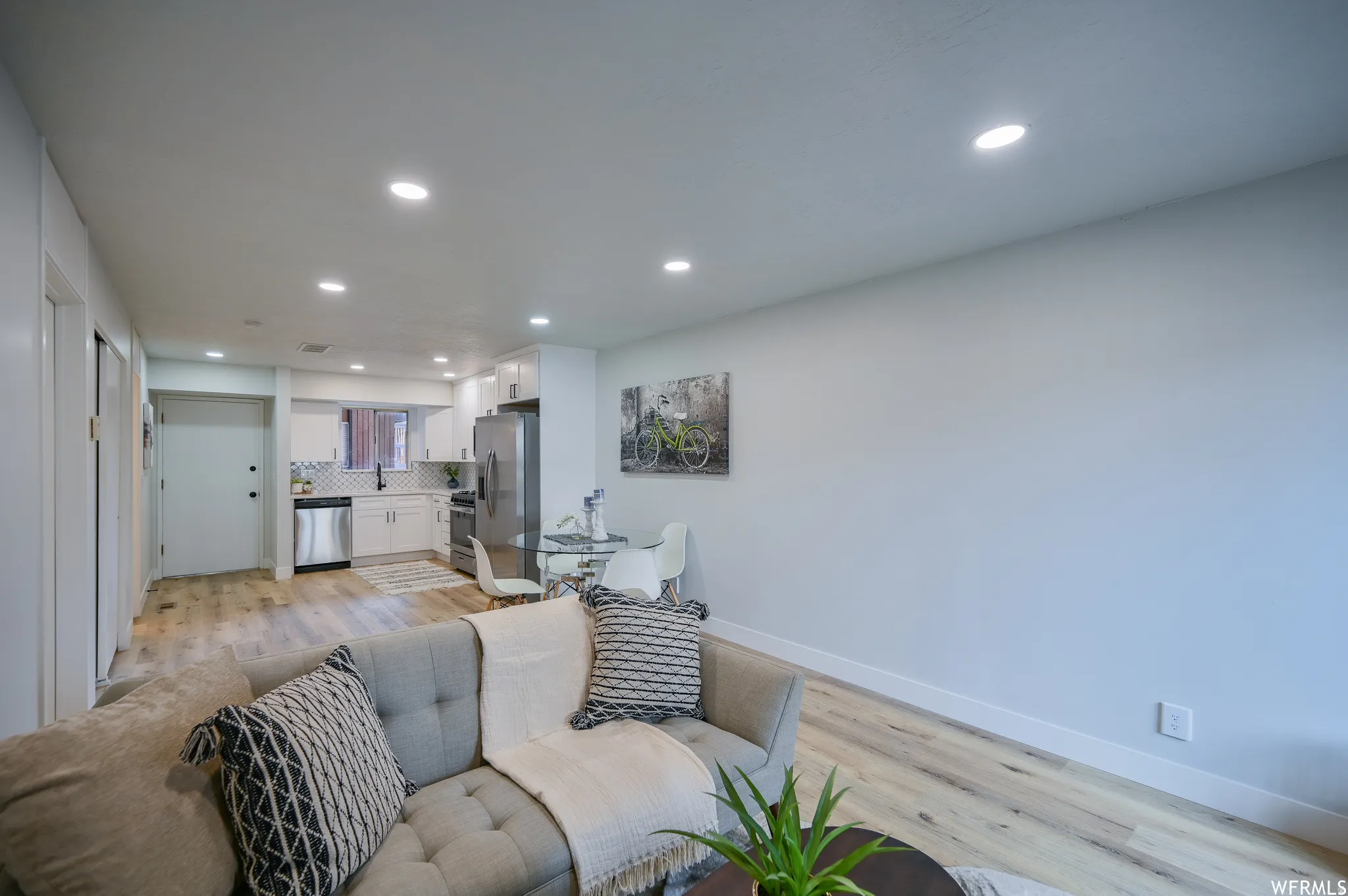 Open-concept living area featuring wood-finish flooring, recessed lighting, and a neutral color palette