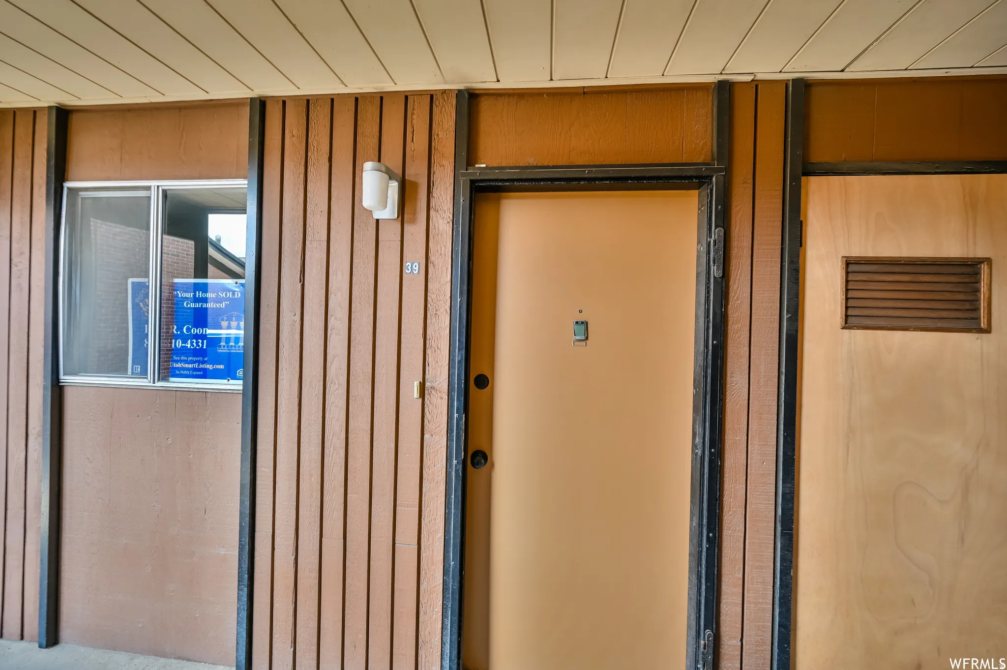 Entryway featuring vertical wood paneling and a light-colored main door