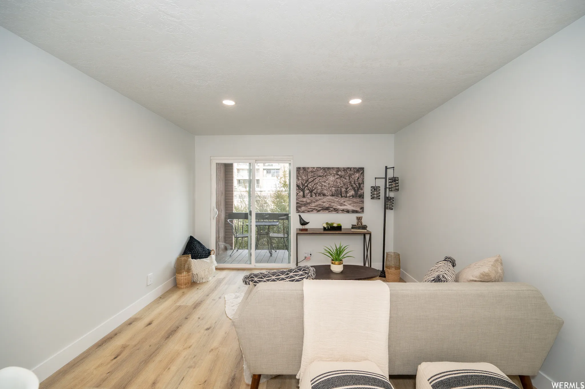 Living area featuring wood-finish flooring, recessed lighting, and a sliding glass door opening to an outdoor balcony