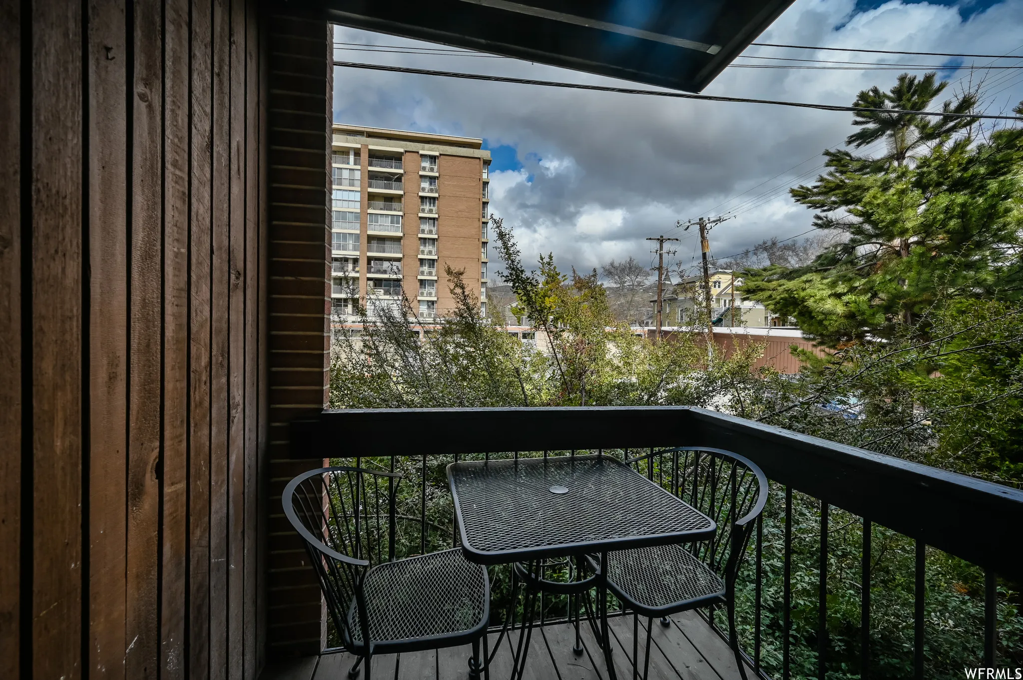 Private balcony featuring wood-finish siding, dark-toned railing, and wood-finish decking
