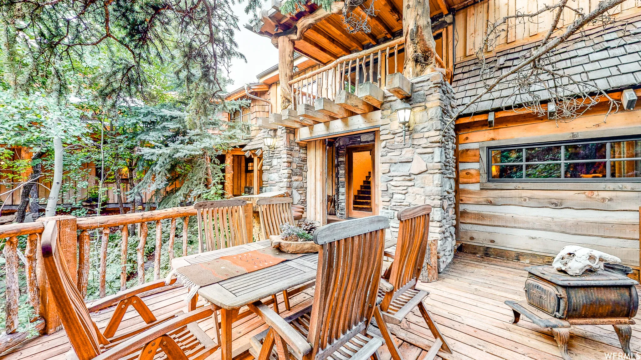 Expansive wood deck with natural wood railing, featuring stone pillar accents and a log cabin style exterior