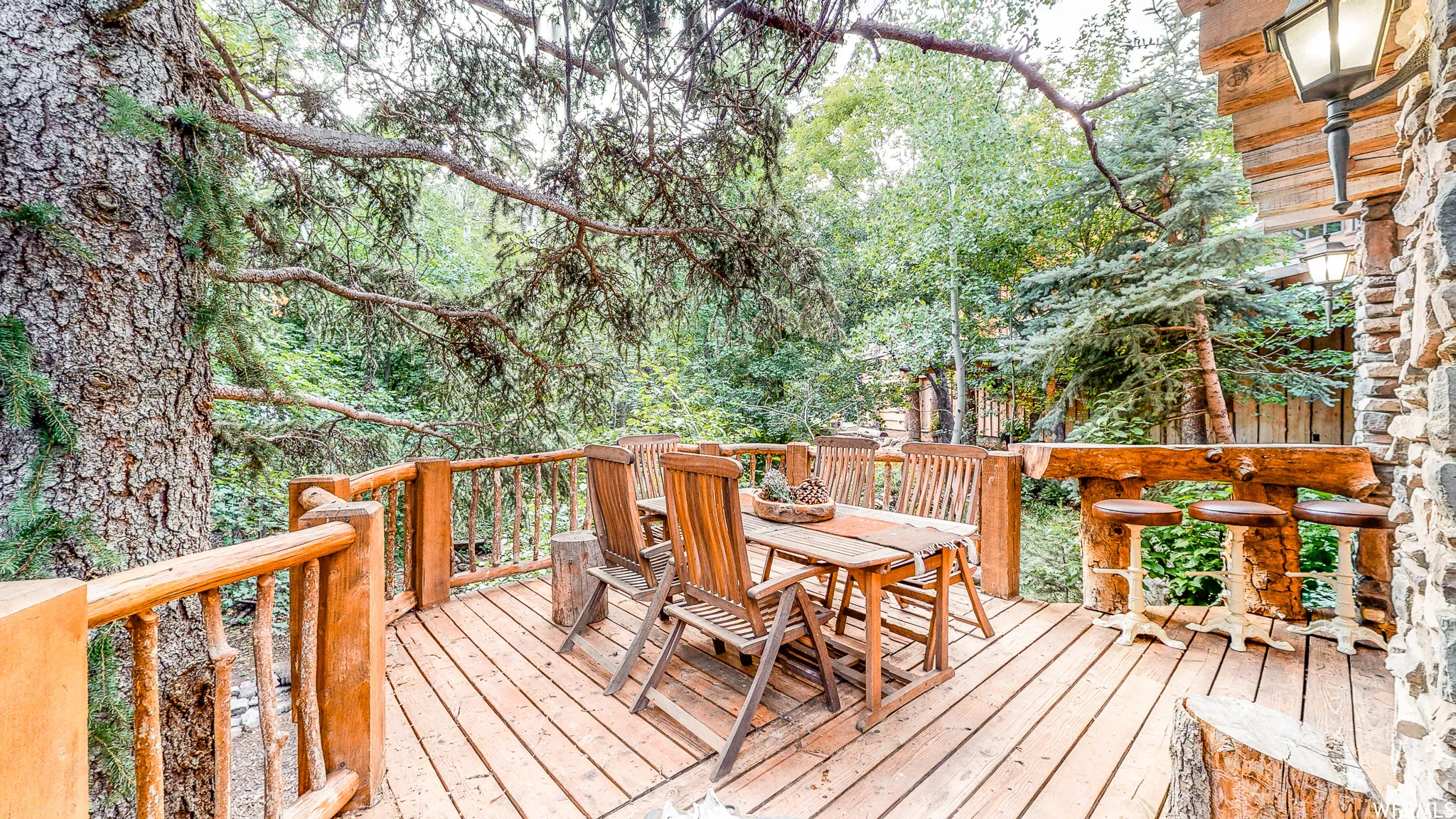 Wood-finish deck featuring a natural wood railing, integrated bar with stools, and stone siding