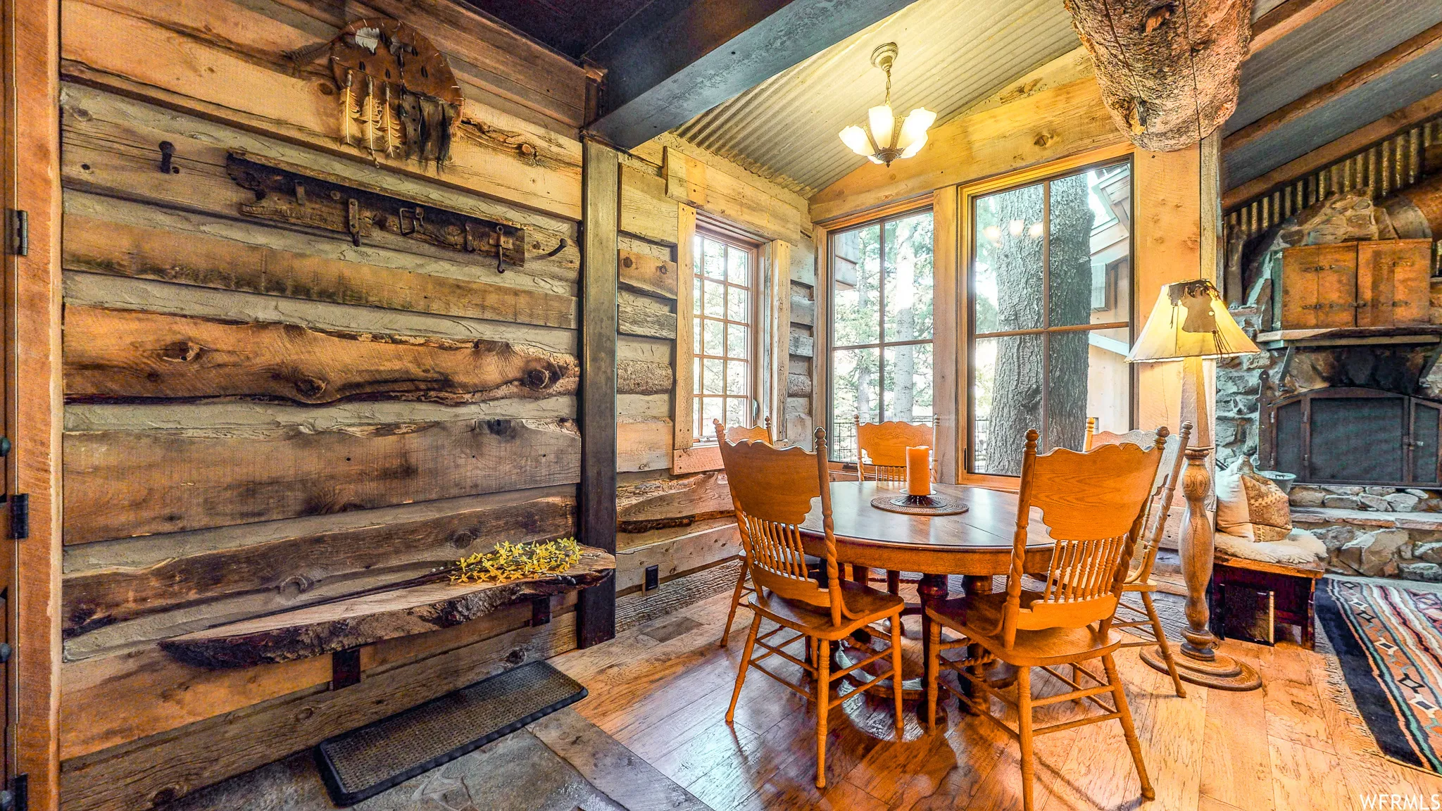 Dining area featuring wood-finish flooring, exposed wood beam ceiling, and a prominent stone fireplace