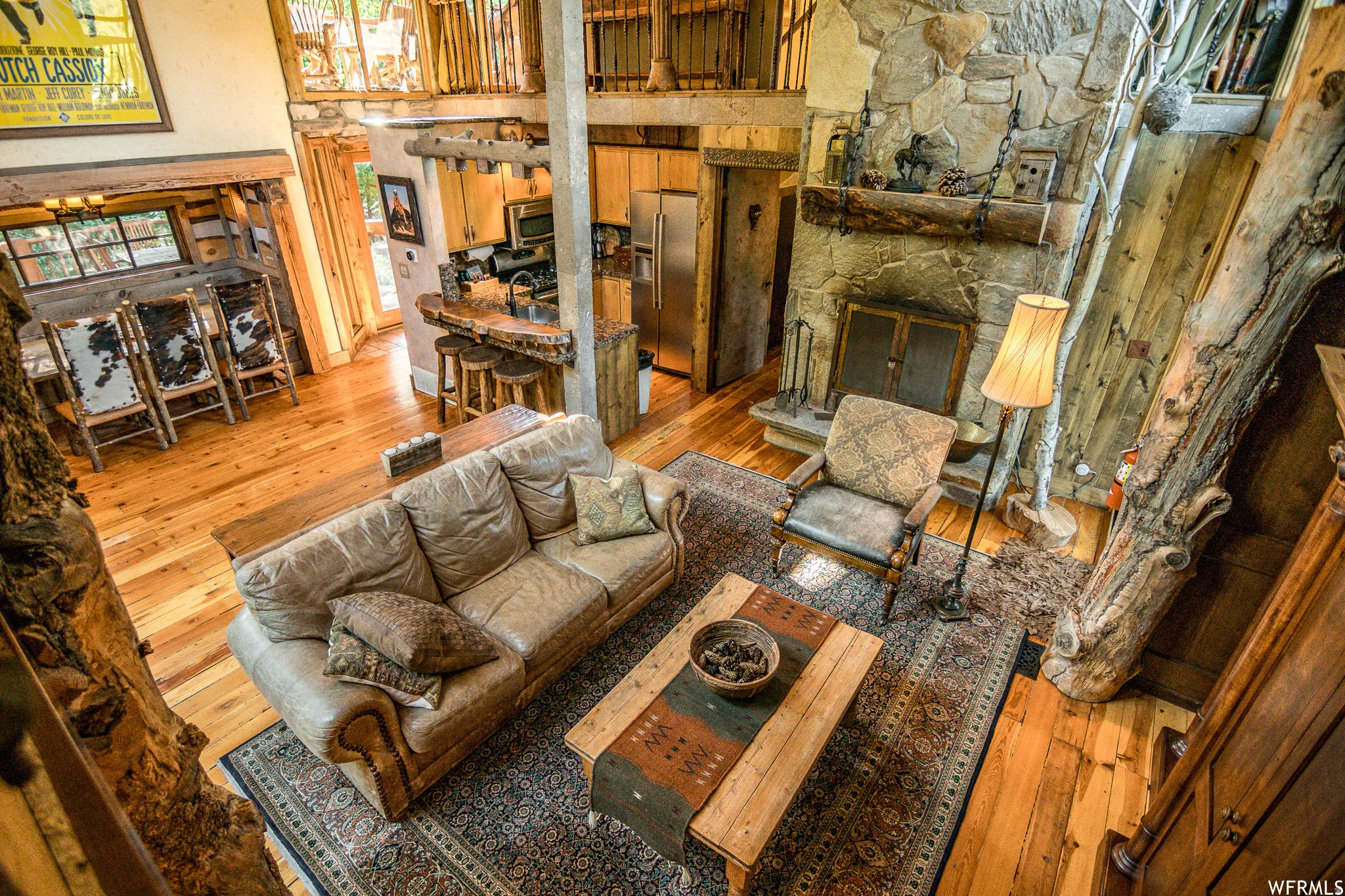 Spacious living area featuring high ceilings, natural wood-finish flooring, and a stone fireplace