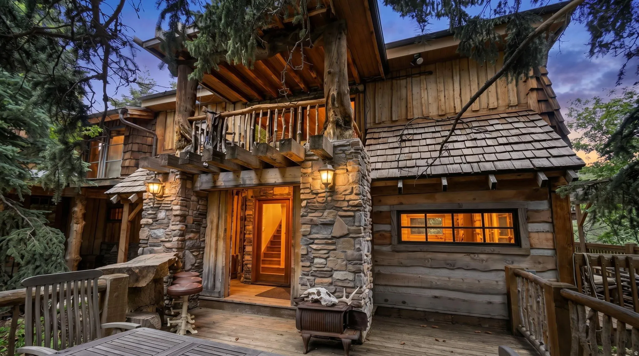 Rustic exterior featuring natural log siding, stone accents, wood shake roofing, and a wooden deck