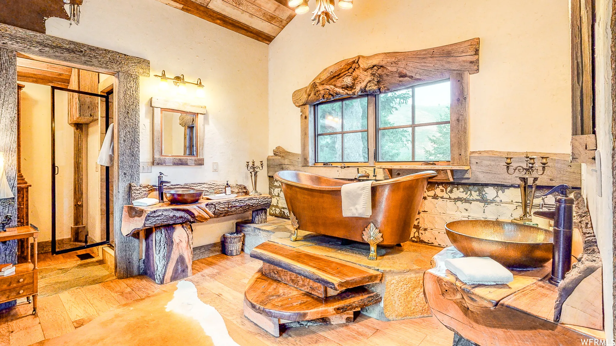 Rustic bathroom featuring a copper freestanding bathtub, natural wood-finish vanity, wood-finish flooring, and a glass-enclosed shower