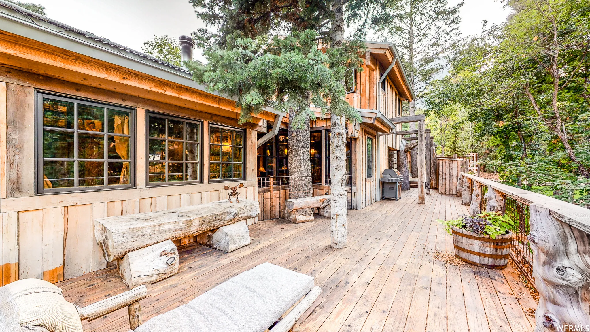 Expansive wood deck with a natural wood railing, featuring a log bench and a built-in barrel planter