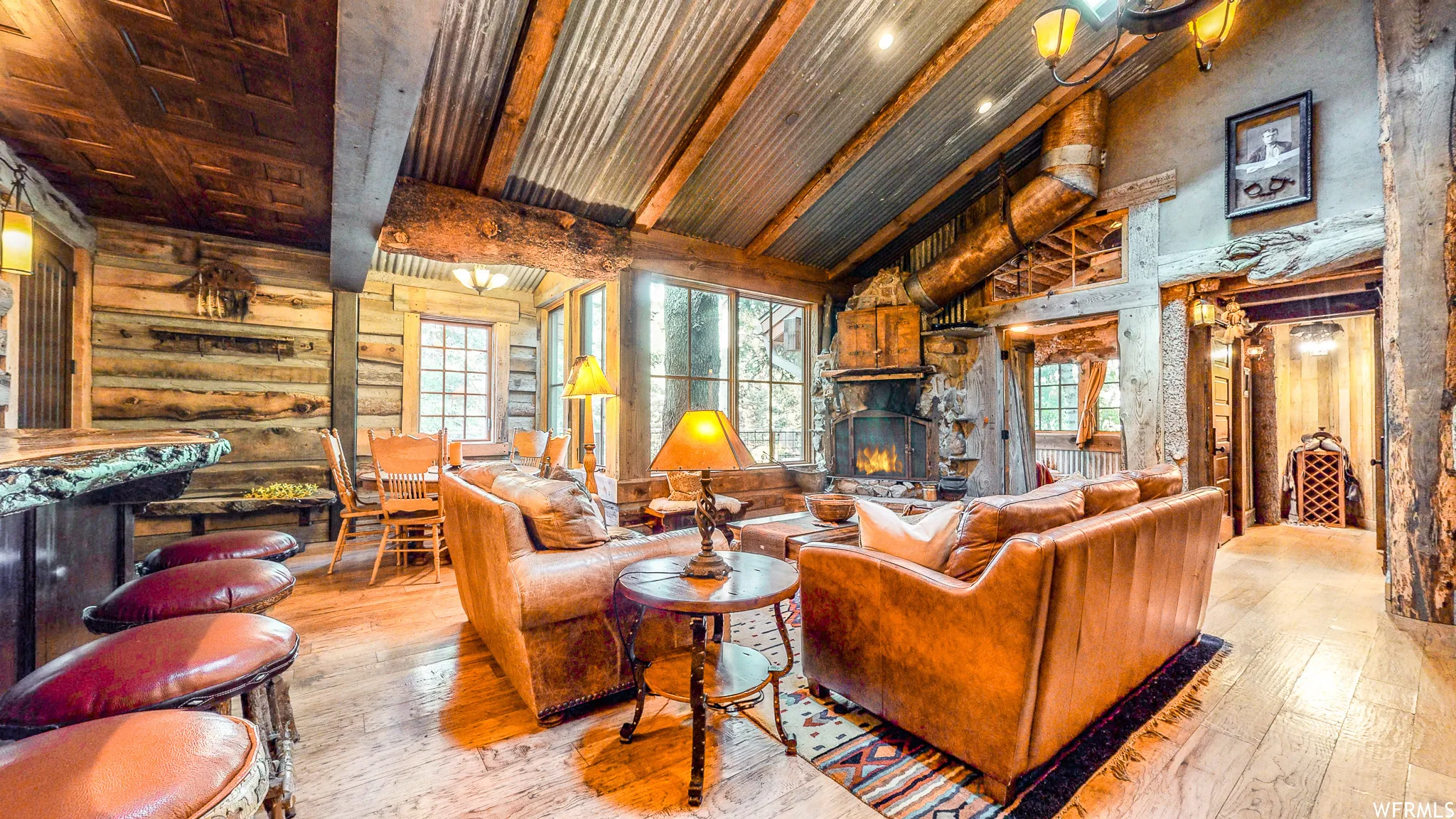 Open-concept living space with exposed wood beams and corrugated metal ceiling