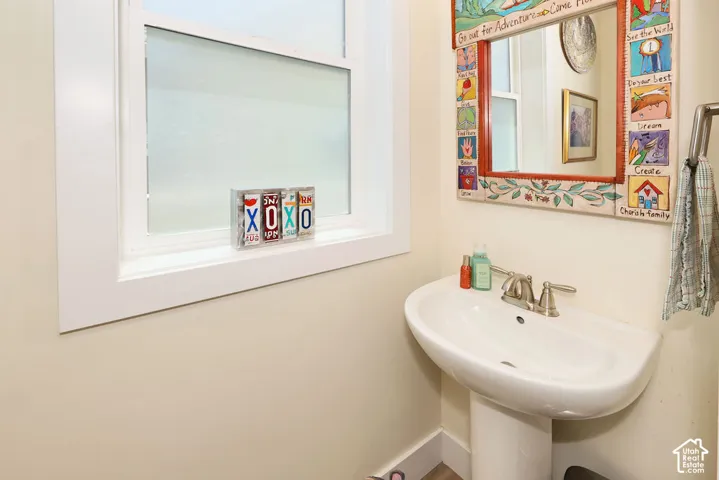 Pedestal sink with dual-handle faucet, frosted window, and wall-mounted towel bar
