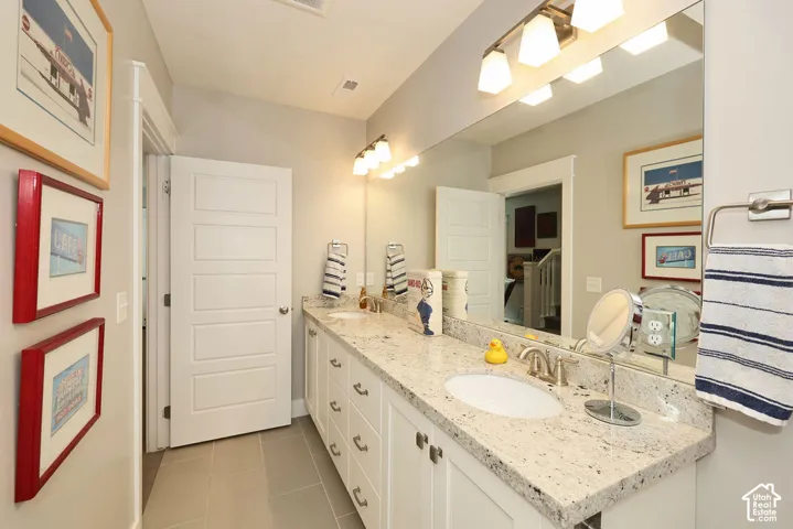 Bathroom featuring a dual vanity with a granite countertop, undermount sinks, and white cabinetry