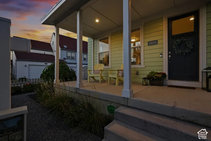 Covered front porch with light green siding and a dark entry door