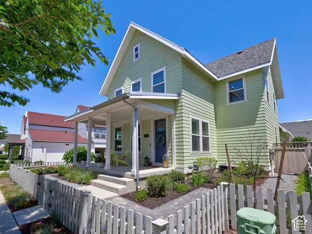 Charming two-story residence featuring light green siding, a covered front porch, and a dormer window