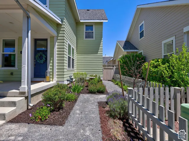 Green siding exterior with a blue entry door, concrete porch, and a gravel walkway