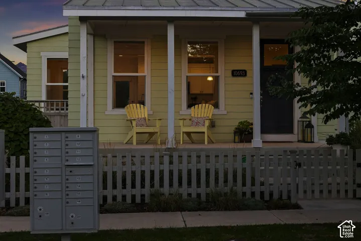 Light green siding exterior with a covered front porch, white-trimmed windows, a dark entry door, and a white picket fence