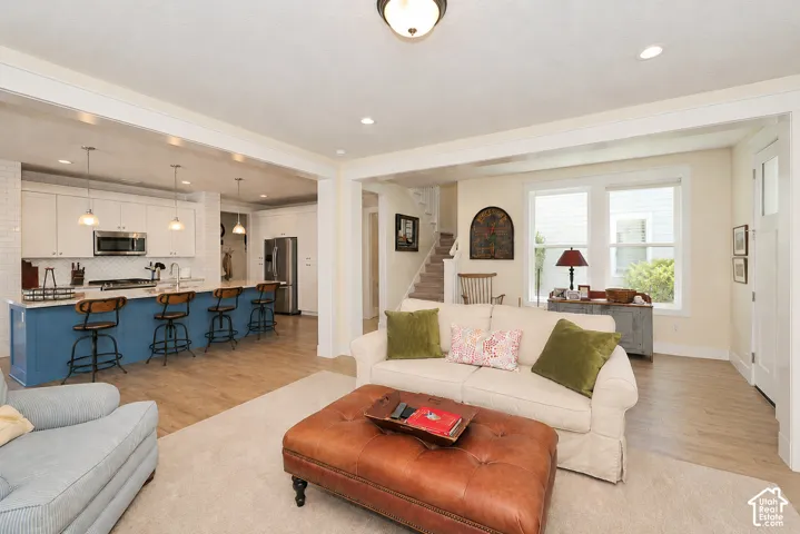 Integrated kitchen and living area featuring wood-finish flooring, recessed lighting, and a white subway tile backsplash
