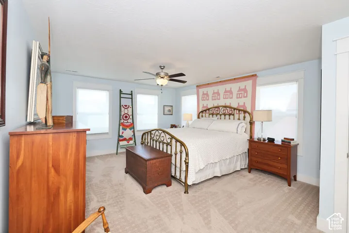 Spacious room featuring light blue walls, soft carpet flooring, and two large windows with white trim
