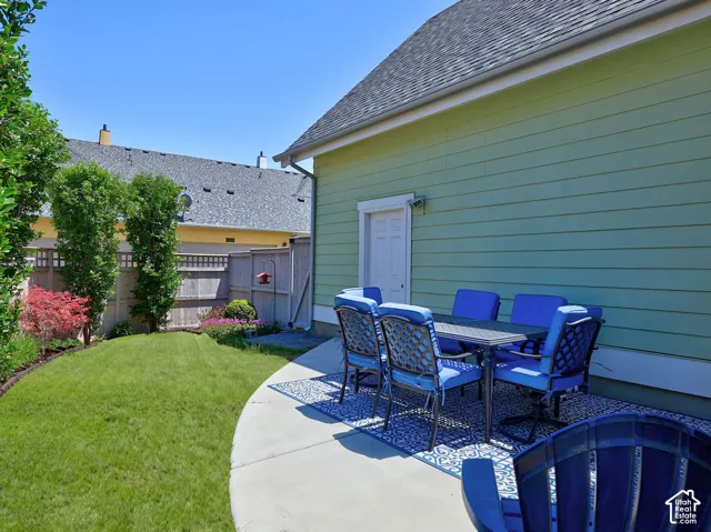 Expansive backyard featuring a concrete patio, a section of manicured lawn, and mature perimeter landscaping