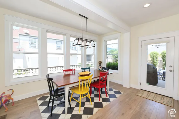 Dining area featuring a wood-finish floor, a wall of multiple windows with white trim, and a full-light door providing exterior access