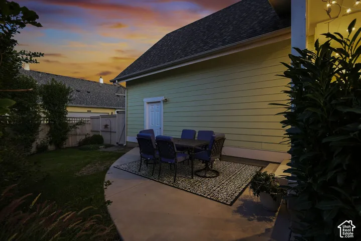 Concrete patio with an exterior entrance and a side yard with manicured grass