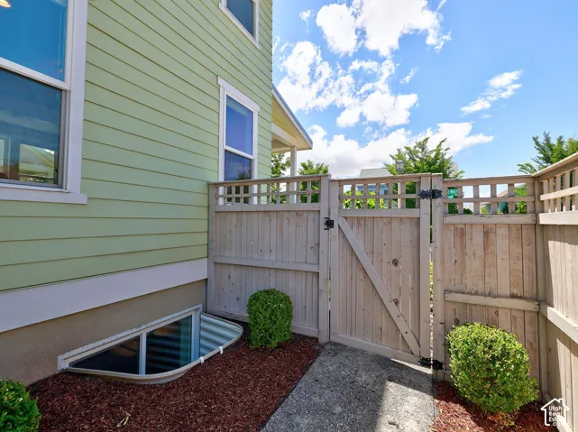 Wood plank privacy fence with lattice top, featuring a secured gate and concrete pathway