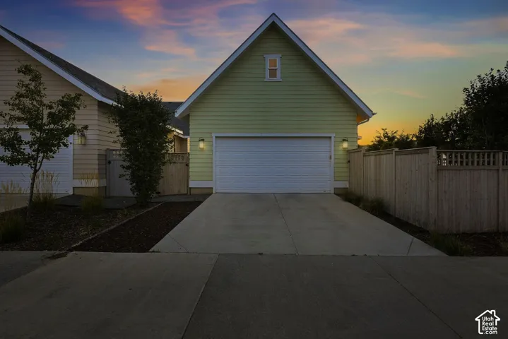 Attached garage with a white roll-up door, featuring exterior sconce lighting and a gable roofline