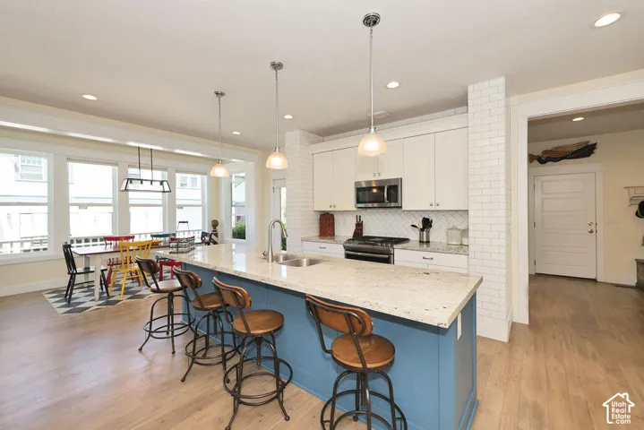 Spacious kitchen featuring a blue-painted island with a light-colored countertop, stainless steel appliances, white cabinetry, and a subway tile backsplash