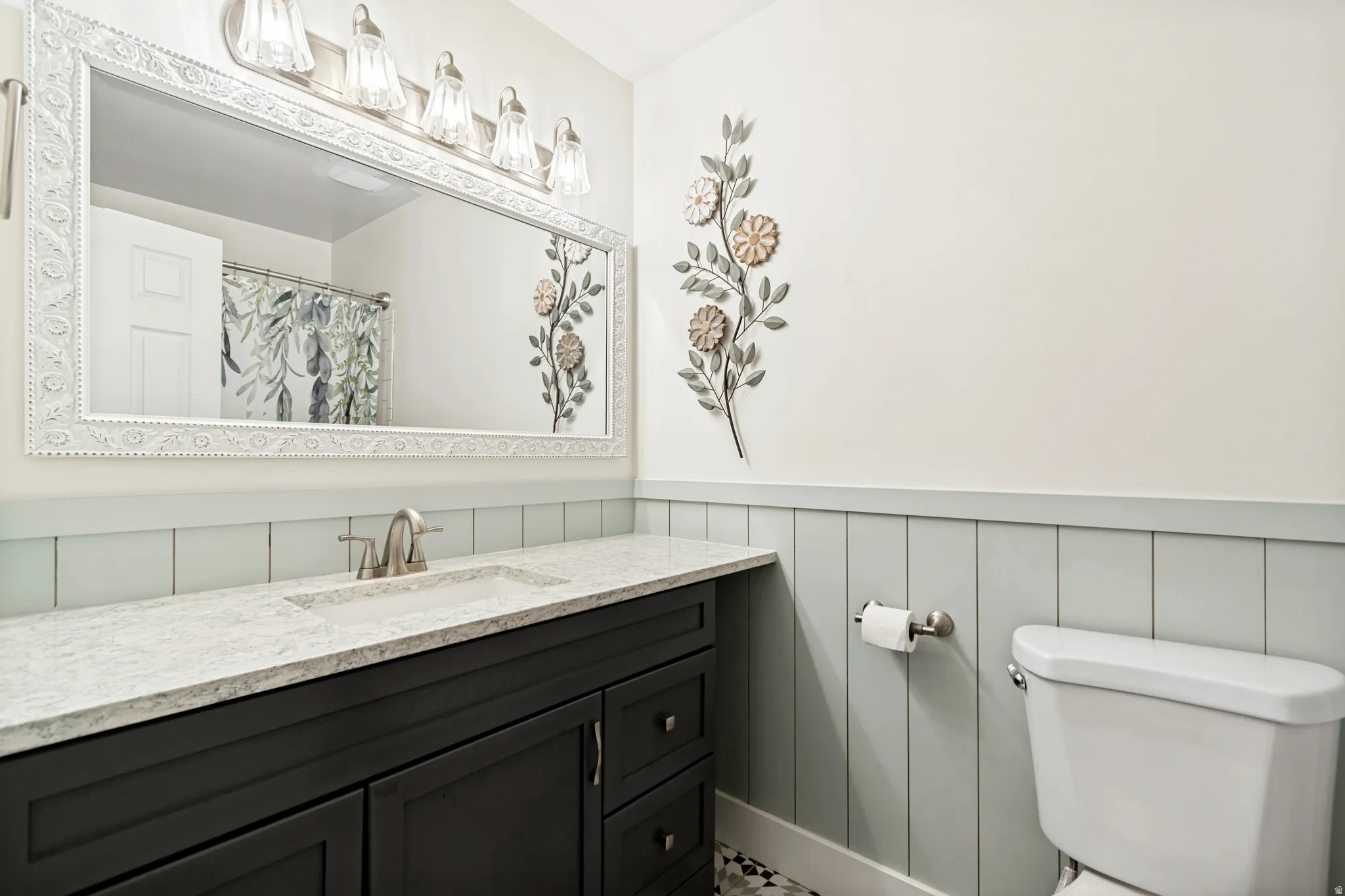Bathroom featuring a dark wood-finish vanity with a light-toned countertop, an undermount sink with a brushed nickel faucet, and a large framed mirror with an overhead light fixture