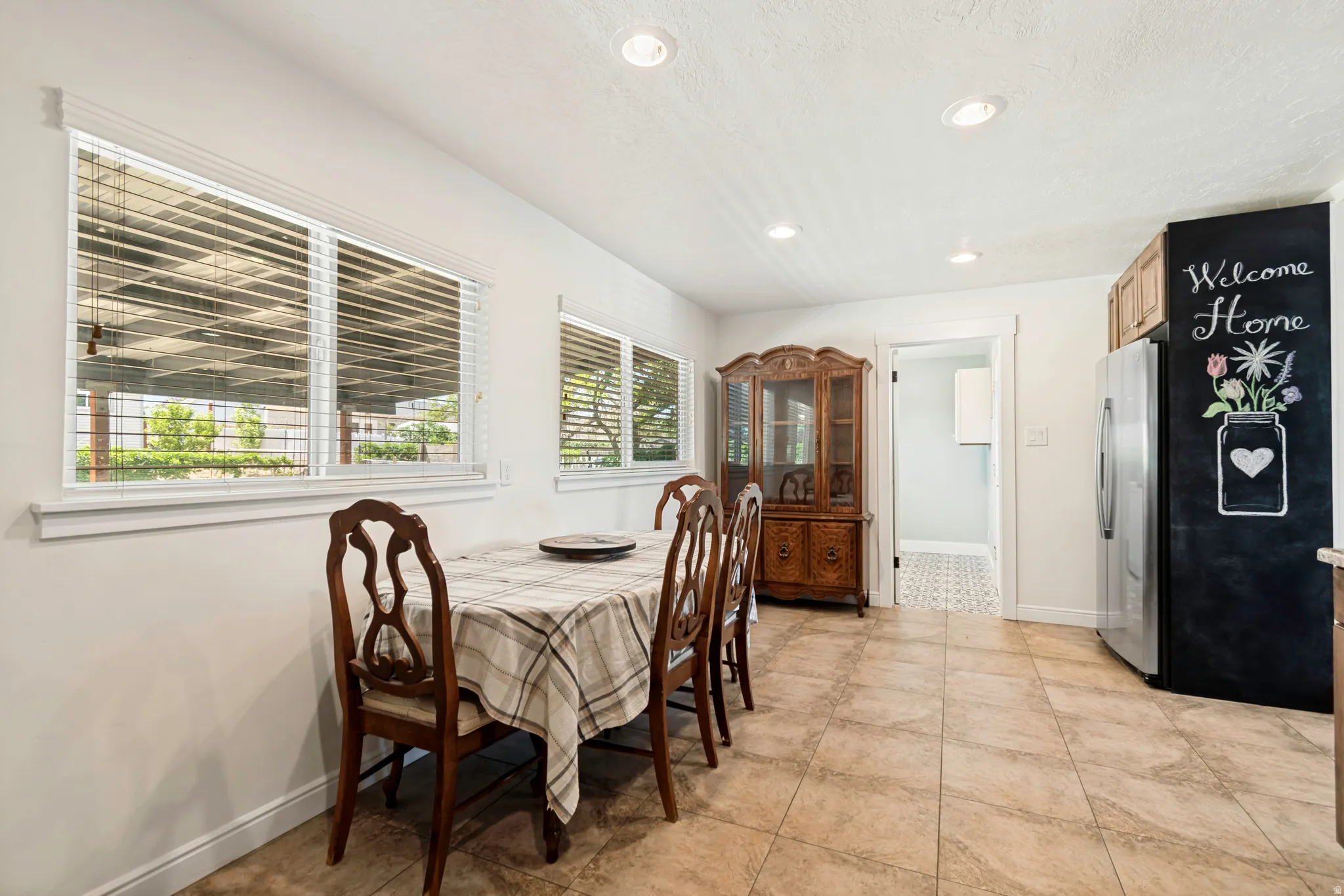 Dining area featuring multiple windows with horizontal blinds, tile flooring, and recessed ceiling lighting